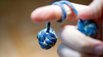 Featured | Monkey fist hanging from a finger | How To Make A Giant Monkey Fist Paracord Project