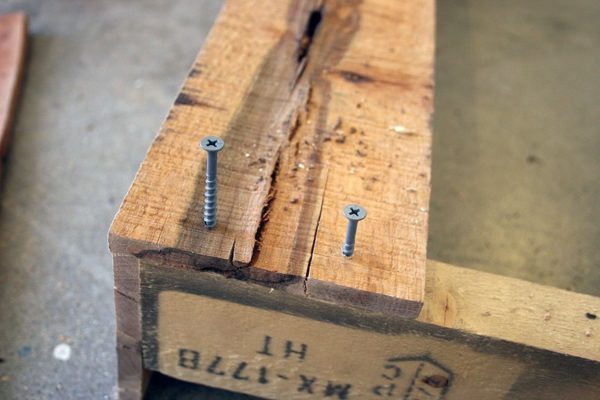 Two screws going into some pallet wood.