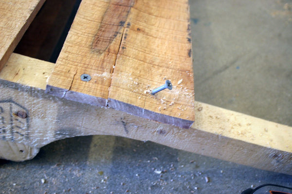 A screw fastening a board to a pallet wine rack.