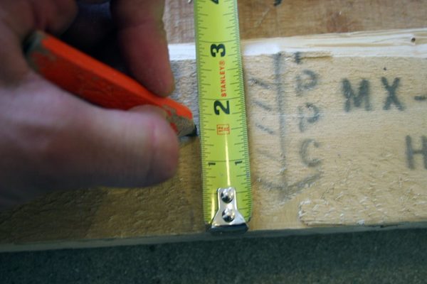 A pencil making a mark on some pallet wood.