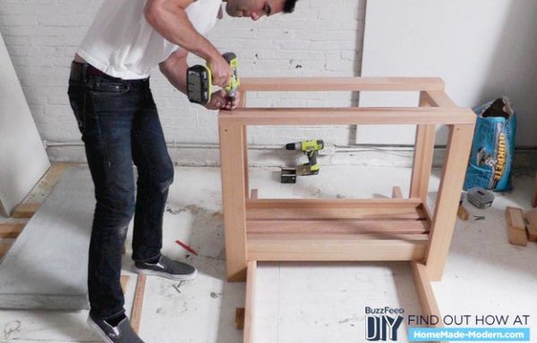 Secure the top tray of the kitchen island to its legs.