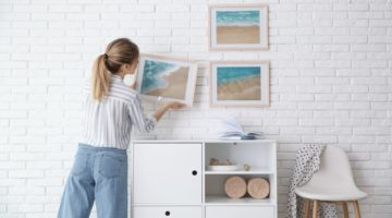 woman decorator hanging picture frame on the wall | Cool Home Decor Wall Art Ideas for You to Craft | wall art | unique wall art | Featured