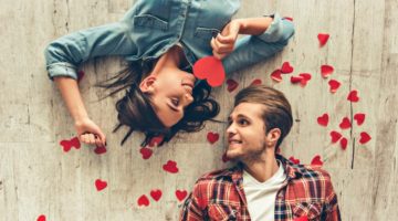 Feature | Smiling couple looking at each other while lying on wooden floor | Valentine's Day Ideas for Him and Her