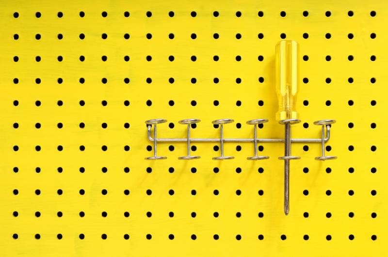 One yellow Phillips screwdriver sits in a rack on a yellow pegboard | DIY Screwdriver Rack