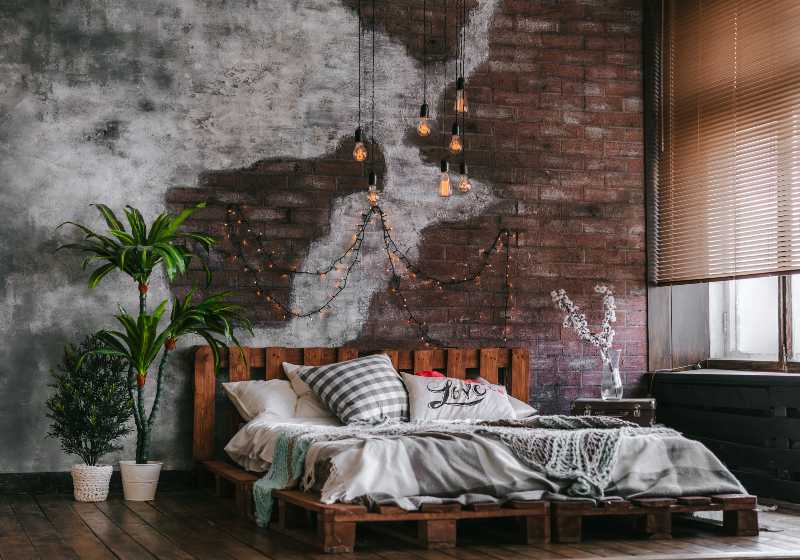 Stylish bedroom in loft style with lots of pillows and lots of light bulbs | DIY Pallet Bed