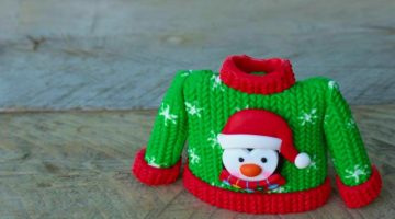 Green and red resin sweater with a penguin wearing Santa hat on it sitting on a natural wood background with writing space | How To Make An Ugly Christmas Sweater | DIY Project | ugly christmas sweater ideas | Featured