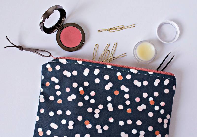 Polka dotted girl makeup bag, golden hairpins, lip balm and pink blusher on the table | DIY Makeup Bag