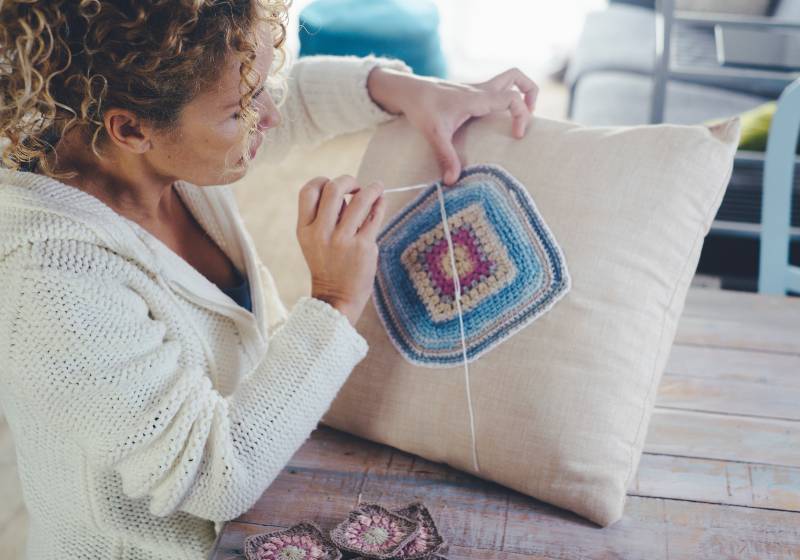 Woman at home doing knit work or crochet on a white pillow | Fat Quarter Pillow