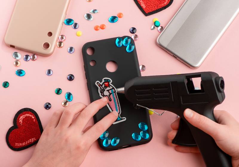 Girl attaching cocktail patch onto black phone case with a glue gun | Phone Cases