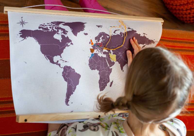 Child embroiders a map of the world with colorful threads from mouline | Embroidered Map