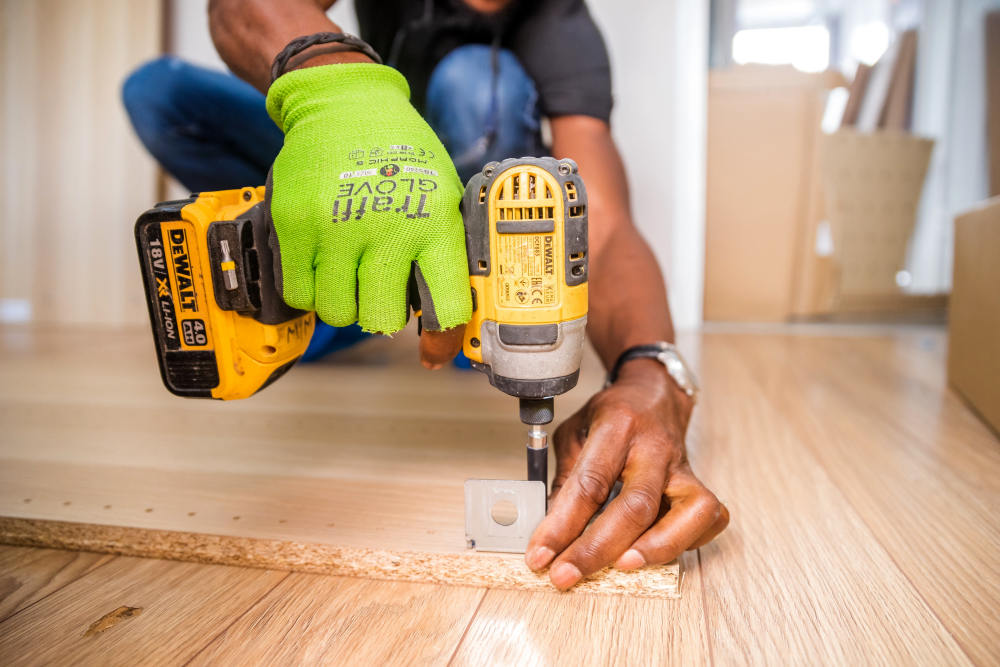 Person using dewalt cordless impact driver on brown board | How To Make A Gallery Wall In Your Home | how to do a gallery wall