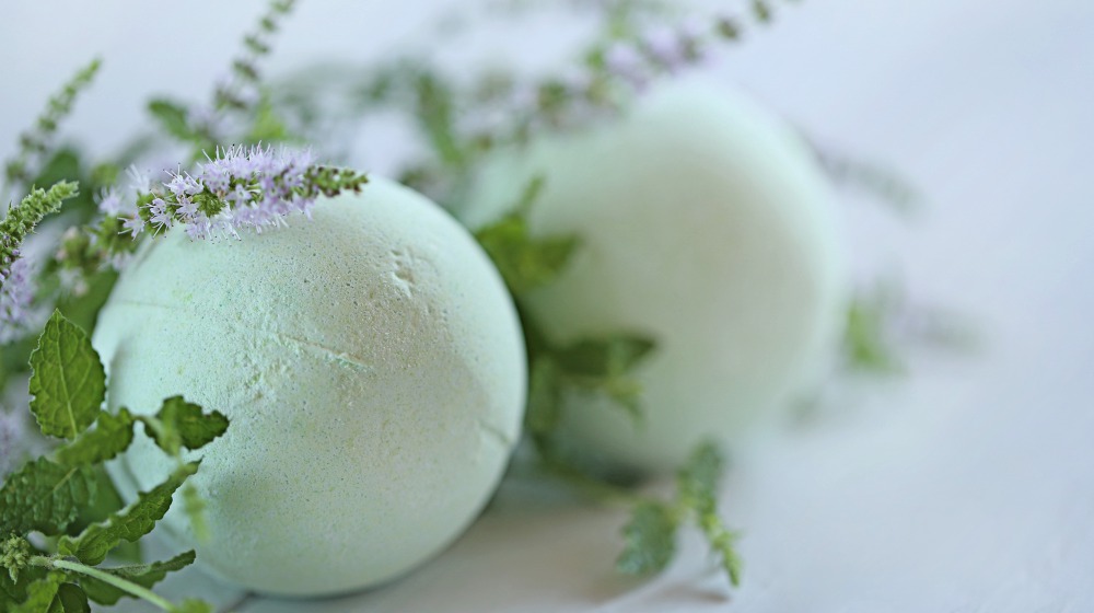 green bath bombs with mint extract and twigs of flowering mint on table | DIY Shamrock Shake Bath Bomb And Soap For A Relaxing St. Patrick’s Day | shamrock shake | diy shamrock shake | Featured