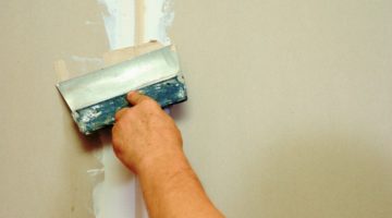 Man putty plasterboard indoor | DIY Drywall Patch To Fix Holes And Dents On Your Walls | Featured