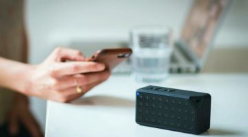 Person Holding Iphone Beside Black Portable Speaker | Create A New DIY Bluetooth Speaker From An Old Laptop | Featured