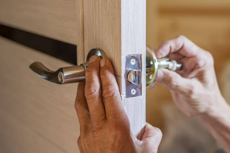 man repairing doorknob closeup workers hands | interior designer hacks