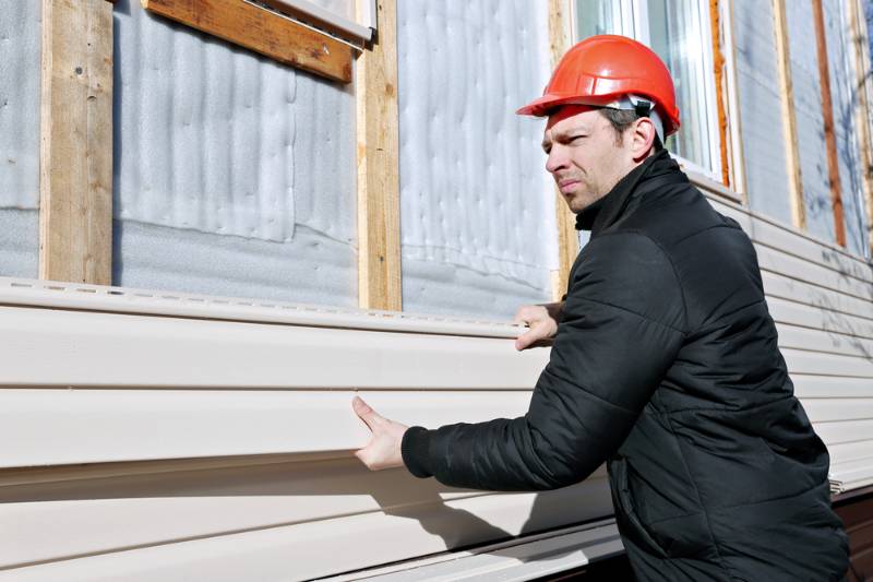 worker-installs-panels-beige-siding-on | vinyl siding repair kits