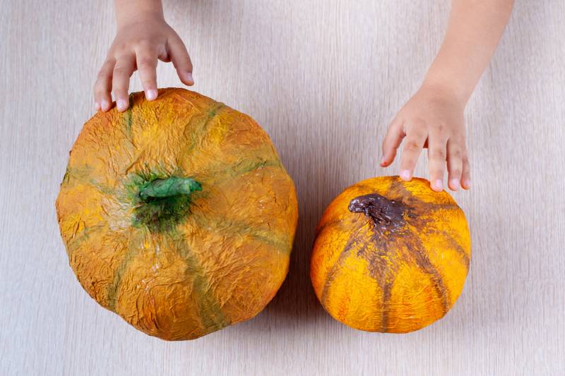 Kinderhände halten hausgemachte orange Papiermache | Herbst Basteln für Kinder