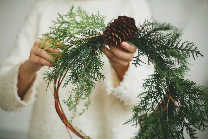 rustic-christmas-wreath-female-hands-florist | pine cone