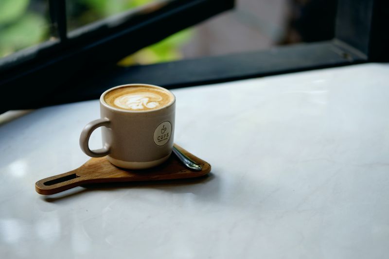 Tasse Kaffee auf beigem Holzpaddel mit Chromlöffel |  Holzschnitzen