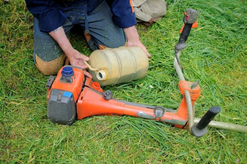 man-fills-fuel-petrol-lawnmower-process | how to fix a lawn mower