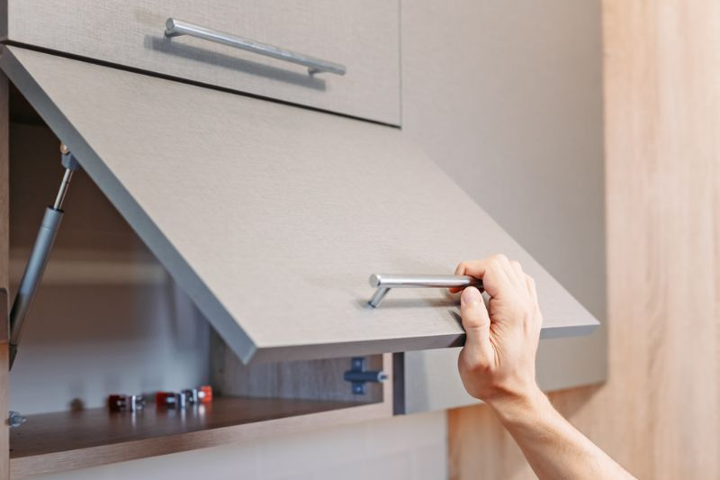 man-hand-open-kitchen-cupboard-handle | hidden storagewall cabinets