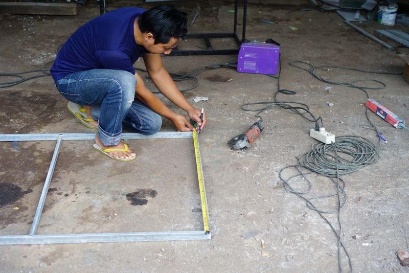squat-male-welder-holding-tape-measure | Roof Rack