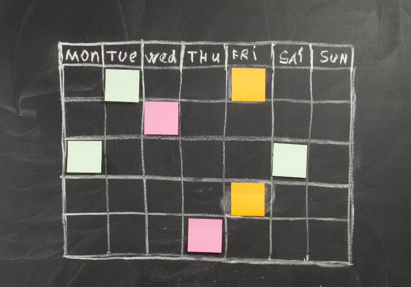 Grid timetable schedule with note paper on black chalkboard background | Chalkboard Calendars