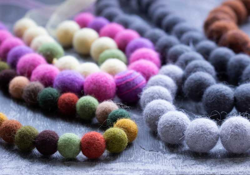 Handmade wool necklace on the background of clothes | Felt Ball Necklaces