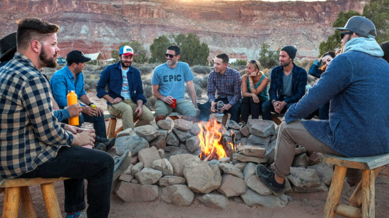 Bonfire surrounded by people | DIY Outdoor Fireplace Ideas To Combat The Winter Chill | outdoor fireplace diy | Featured