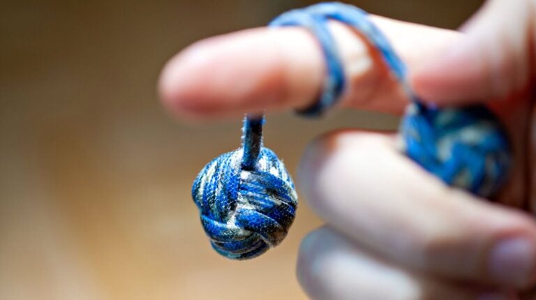 Featured | Monkey fist hanging from a finger | How To Make A Giant Monkey Fist Paracord Project
