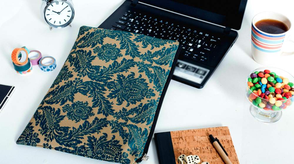Black laptop on white desk with laptop case, candy, diary, clock | Laptop Case DIY Project You Can Do With Your Kids