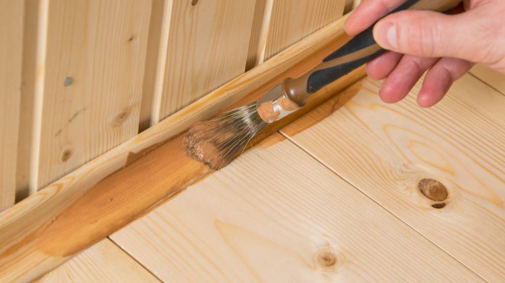close-applying-dark-varnish-on-wooden | How To Paint Baseboards