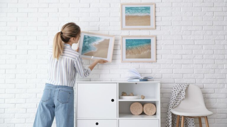 woman decorator hanging picture frame on the wall | Cool Home Decor Wall Art Ideas for You to Craft | wall art | unique wall art | Featured