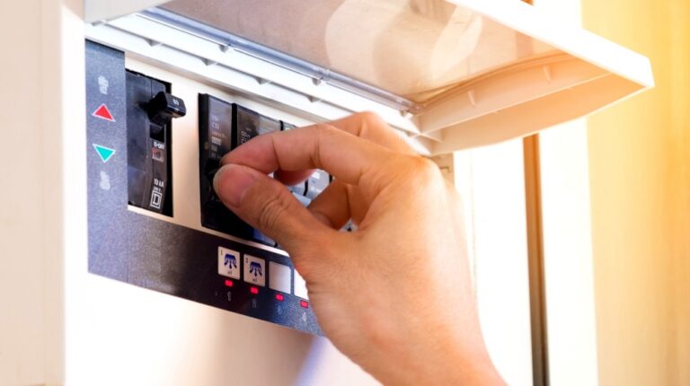 electrician on hand open circuit breaker | How Fuses and Circuit Breakers Can Protect Your Home | featured