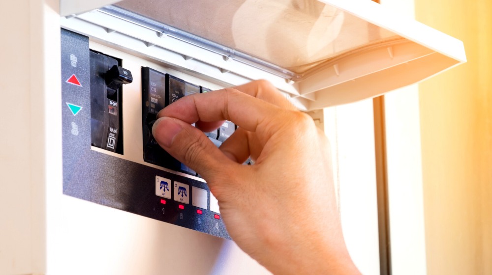 electrician on hand open circuit breaker | How Fuses and Circuit Breakers Can Protect Your Home | featured