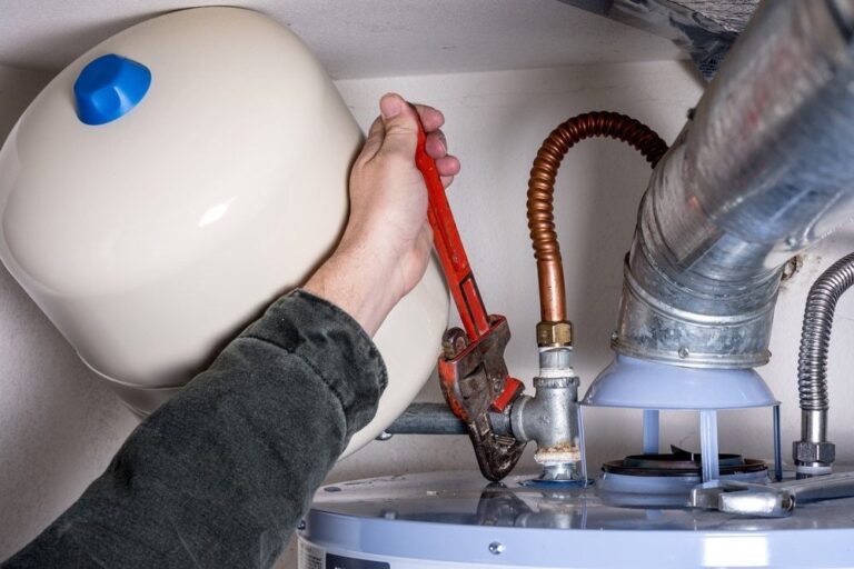 man-works-on-hot-water-heater | 18 Helpful Tips for Water Heater Tune Up To Save Up This Winter | Featured