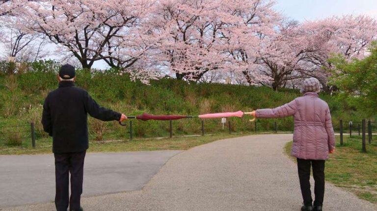 Two people (a man and a woman) stand apart holding two umbrellas | Funny DIY Social Distancing Devices And How To Make Them | Featured