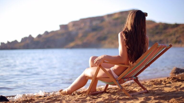 woman sitting on the beach | How To Make Your Own Homemade Sunscreen Using Natural Ingredients | natural spf oils | featured