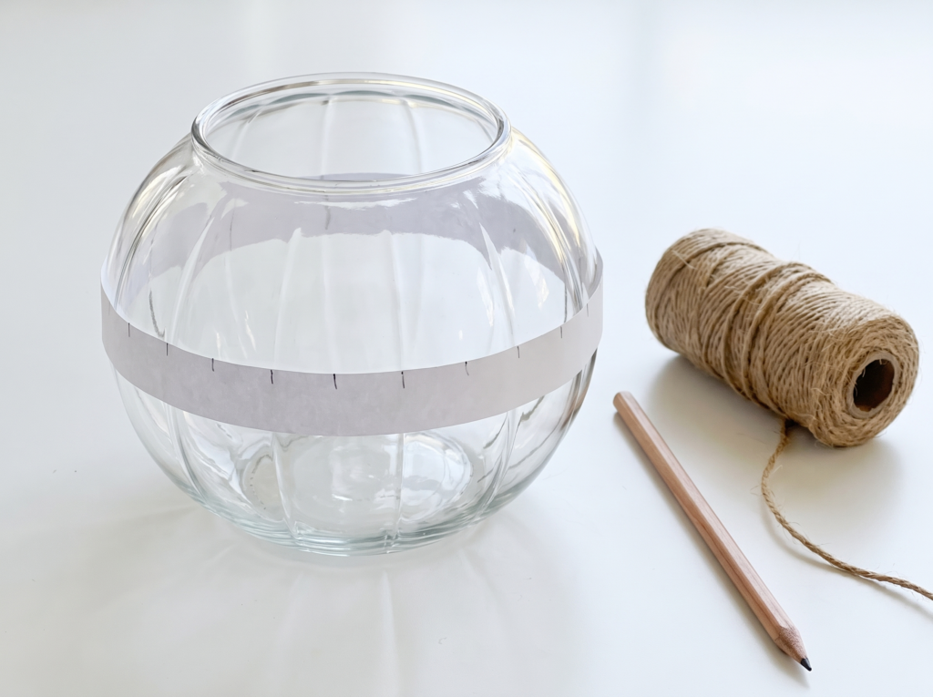 Bare round glass bowl with a marked paper strip taped around it as a twine spacing guide