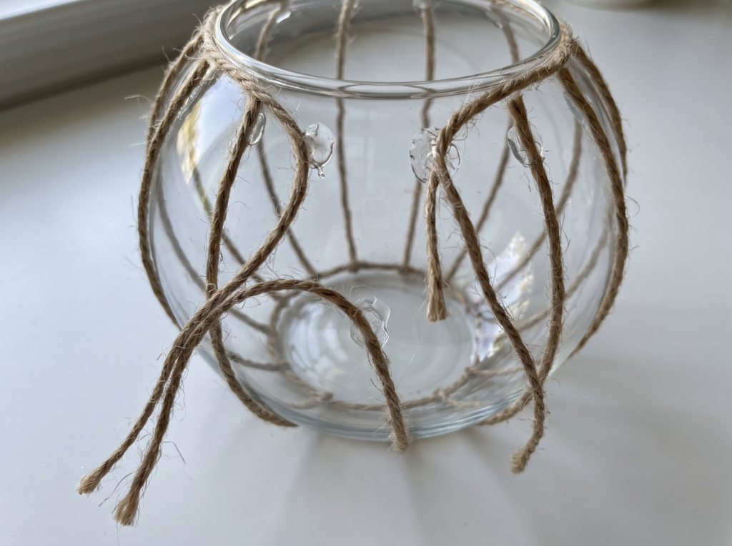 Jute twine ribs peeling and sagging away from a glass bowl with dried hot glue blobs where the wrap failed