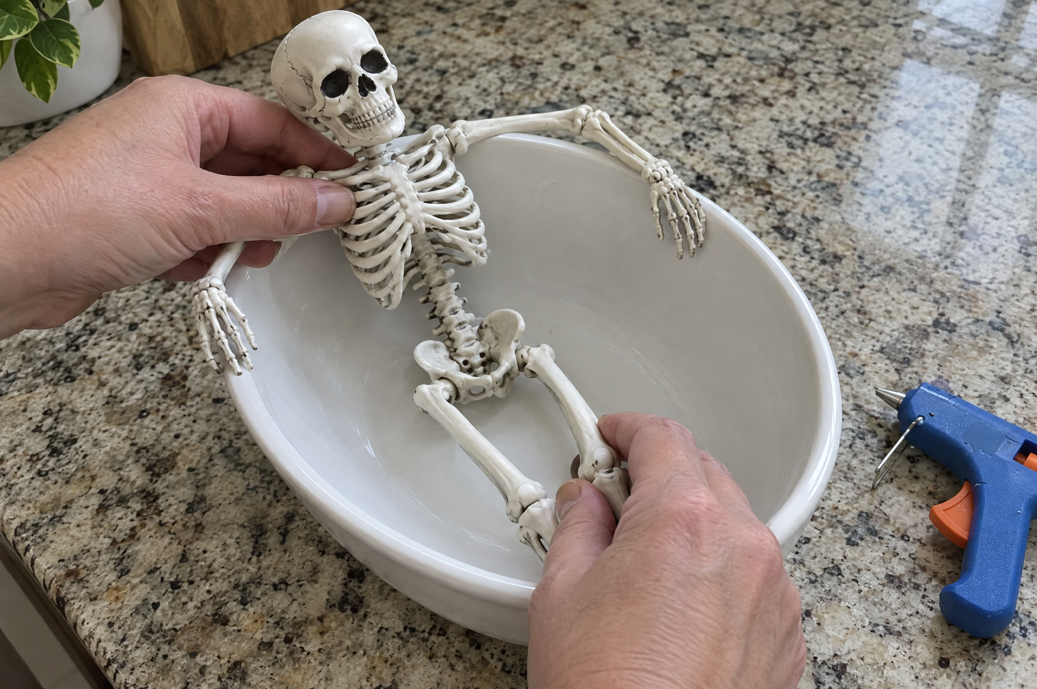 Gluing a mini skeleton into an empty ceramic bowl before adding wax