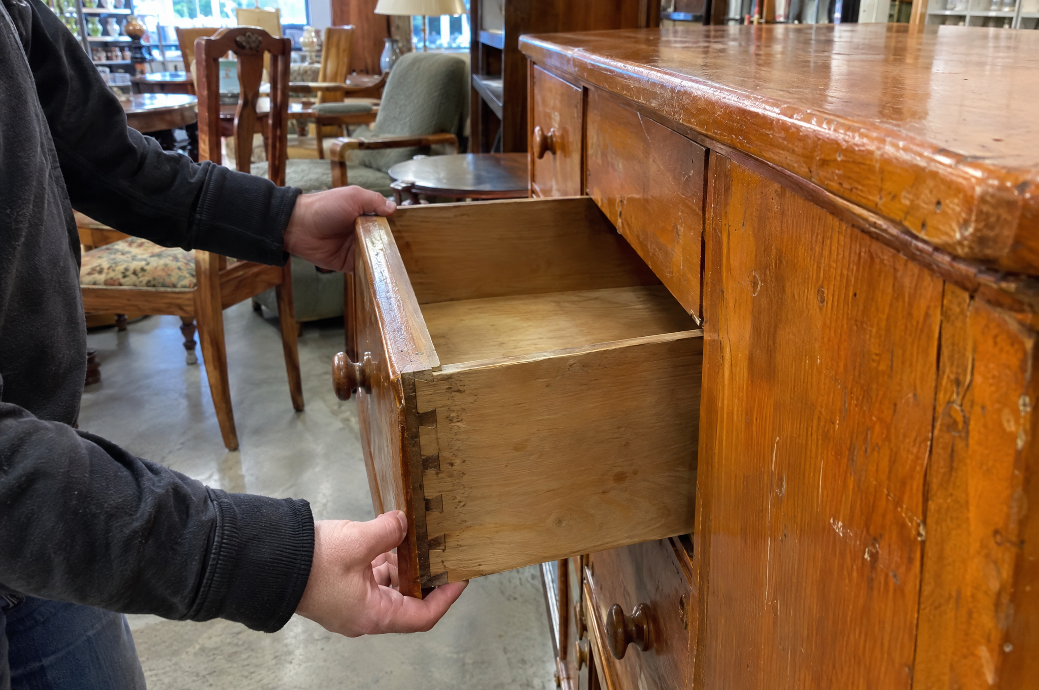 Checking dovetail drawer joints on a thrift store dresser before buying it to flip